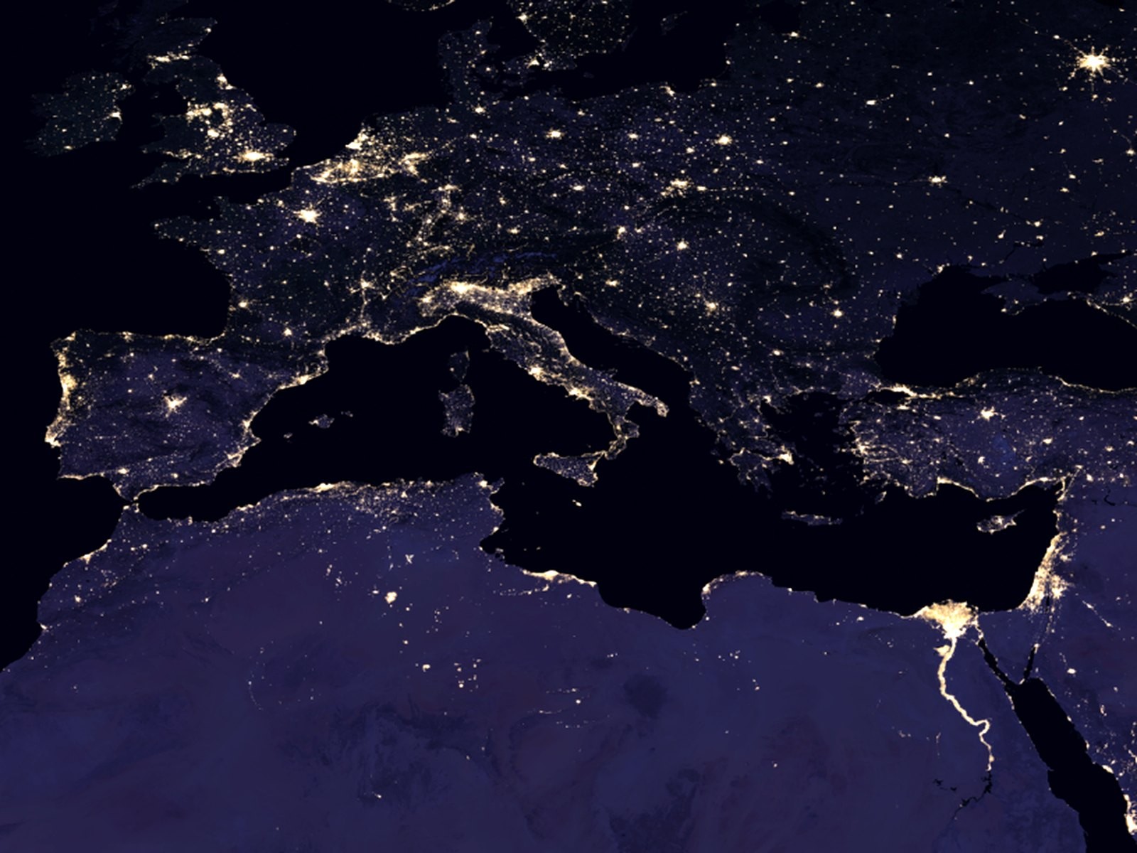 Earth at night from space showing illuminated cities and communities