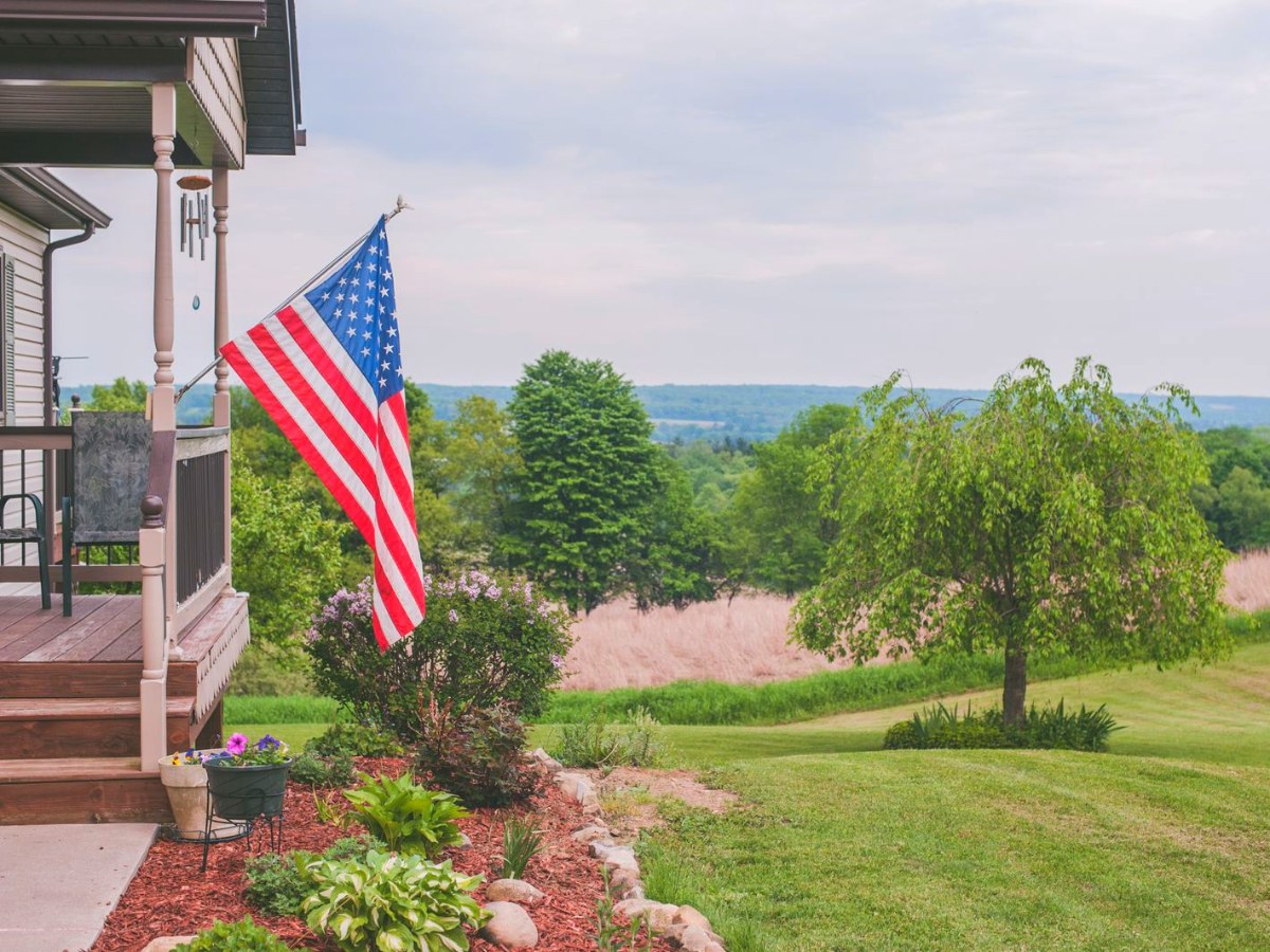 American flag on the front porch of a home overlooking the Upstate New York countryside